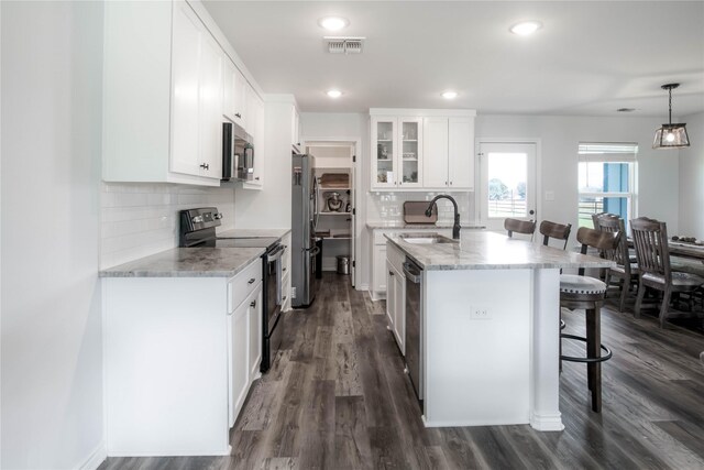 kitchen with a kitchen breakfast bar, light stone counters, stainless steel appliances, sink, and white cabinets