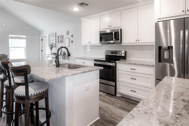 kitchen with light stone countertops, dark hardwood / wood-style floors, lofted ceiling, and appliances with stainless steel finishes