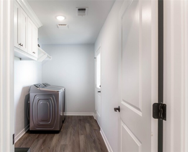 laundry area with washing machine and clothes dryer, cabinets, and dark hardwood / wood-style floors