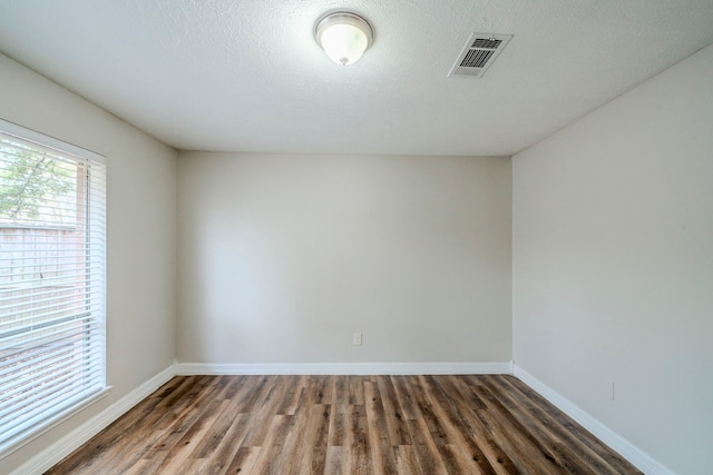 empty room featuring a textured ceiling and dark wood-type flooring