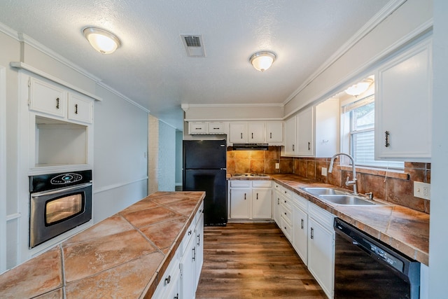 kitchen with decorative backsplash, sink, black appliances, white cabinets, and tile counters