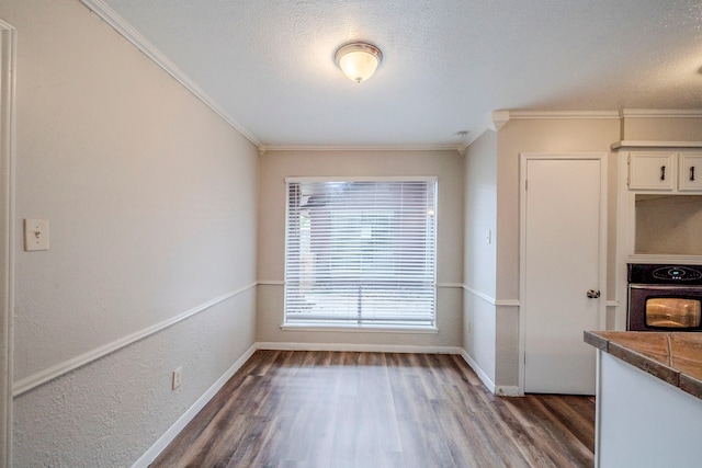 unfurnished dining area with crown molding, dark hardwood / wood-style flooring, and a textured ceiling