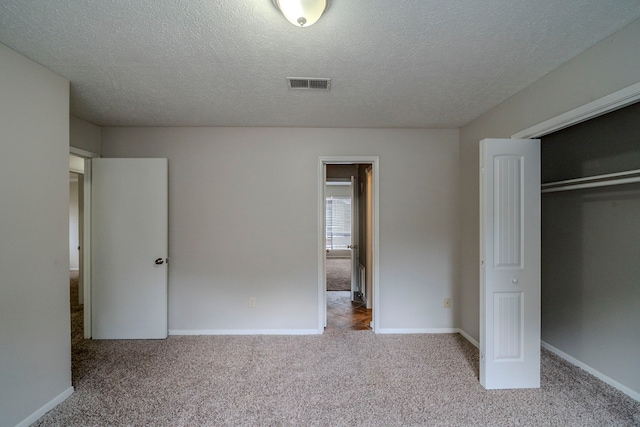 unfurnished bedroom with light carpet, a closet, and a textured ceiling