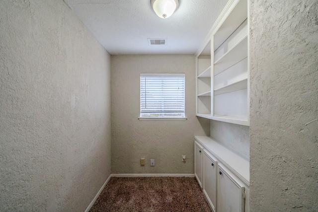 interior space featuring dark colored carpet and a textured ceiling