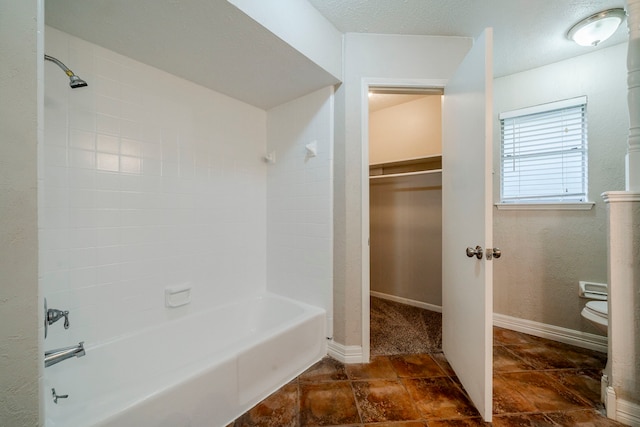 bathroom featuring toilet and tiled shower / bath