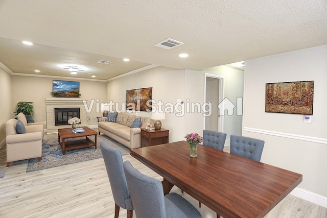 dining area featuring crown molding, light hardwood / wood-style flooring, and a textured ceiling