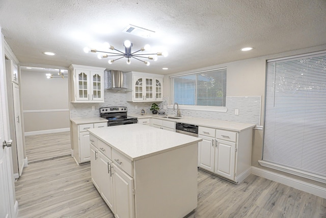 kitchen with a center island, white cabinets, wall chimney exhaust hood, a textured ceiling, and appliances with stainless steel finishes