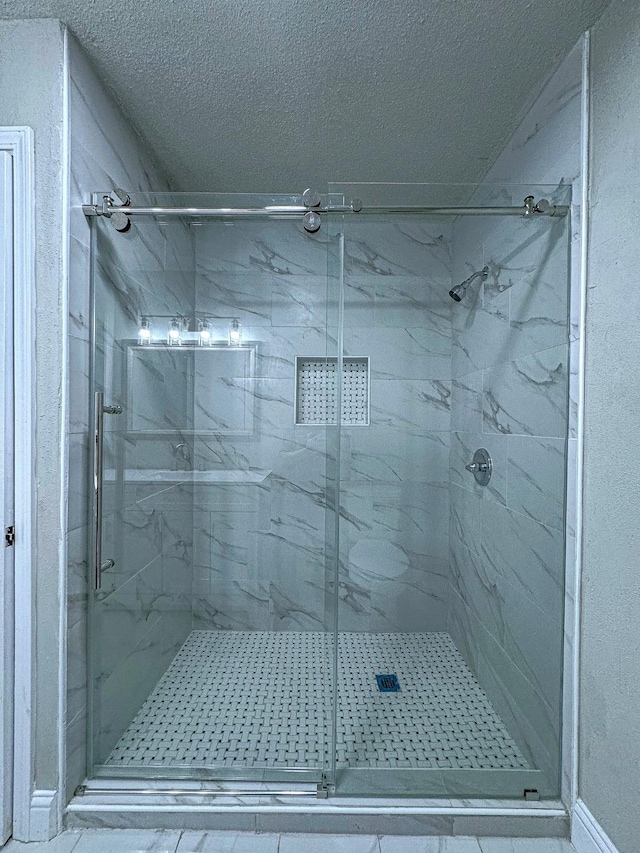 bathroom featuring a textured ceiling and a shower with shower door