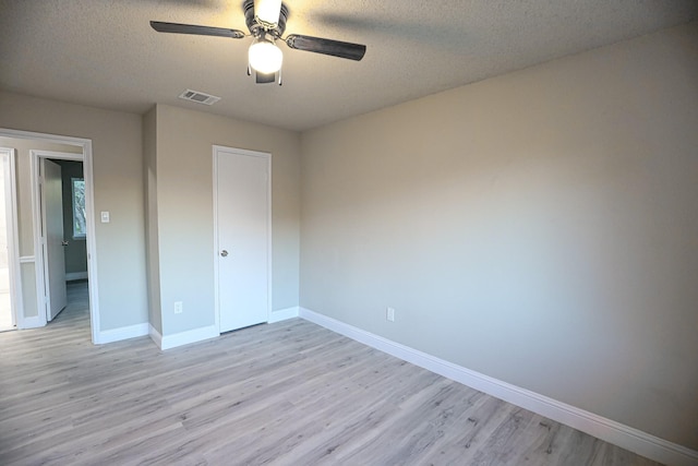 unfurnished bedroom with ceiling fan, a closet, a textured ceiling, and light wood-type flooring