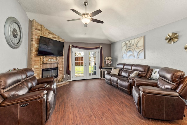 living room with french doors, a brick fireplace, vaulted ceiling, ceiling fan, and dark hardwood / wood-style floors