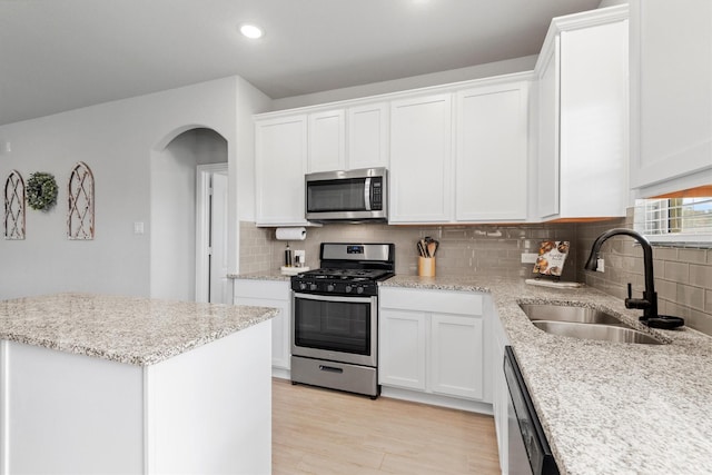 kitchen featuring sink, decorative backsplash, light wood-type flooring, white cabinetry, and stainless steel appliances