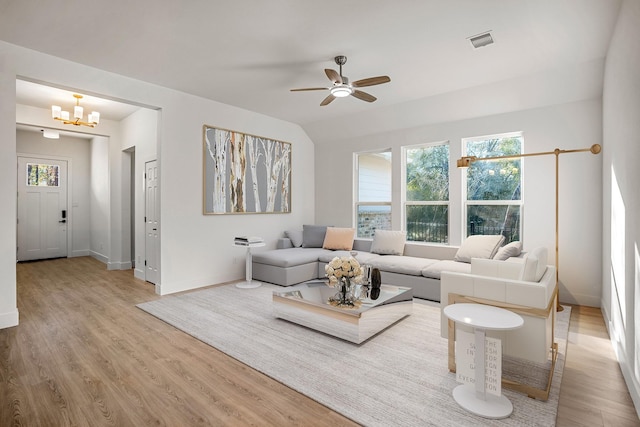 living room featuring ceiling fan with notable chandelier and light hardwood / wood-style flooring