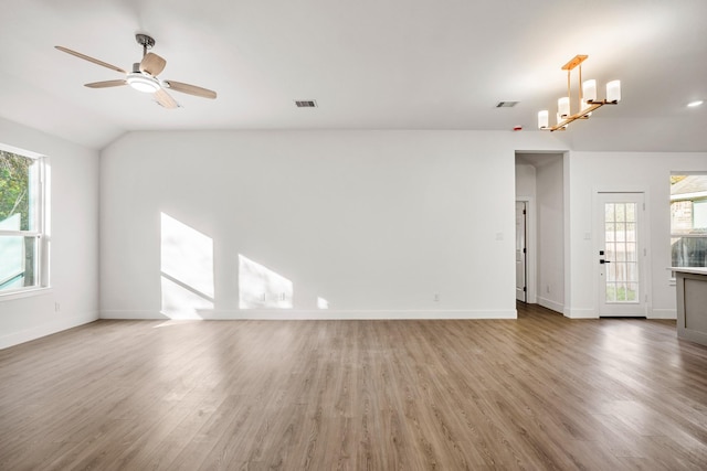 unfurnished living room with plenty of natural light, wood-type flooring, ceiling fan with notable chandelier, and vaulted ceiling