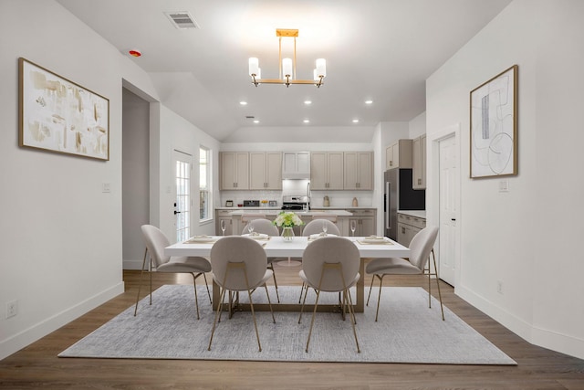 dining room with lofted ceiling, dark hardwood / wood-style floors, and an inviting chandelier