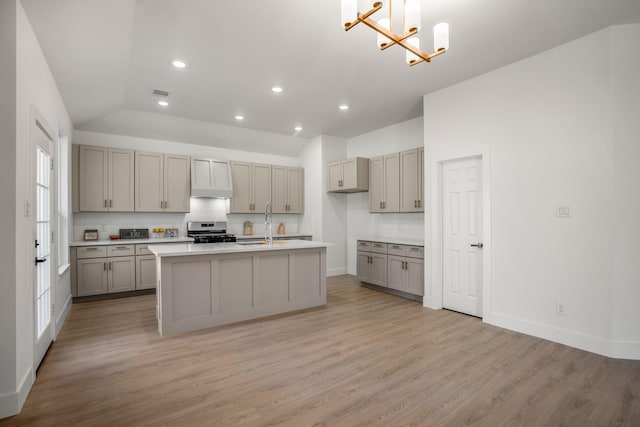 kitchen with pendant lighting, light hardwood / wood-style floors, gray cabinets, and stainless steel gas range