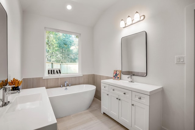 bathroom featuring a washtub, lofted ceiling, and vanity