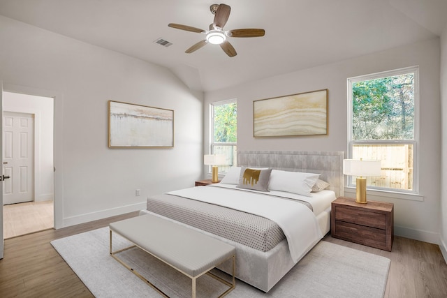 bedroom featuring hardwood / wood-style flooring, ceiling fan, vaulted ceiling, and multiple windows