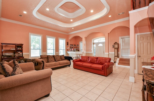 living room with crown molding, a tray ceiling, and light tile patterned floors