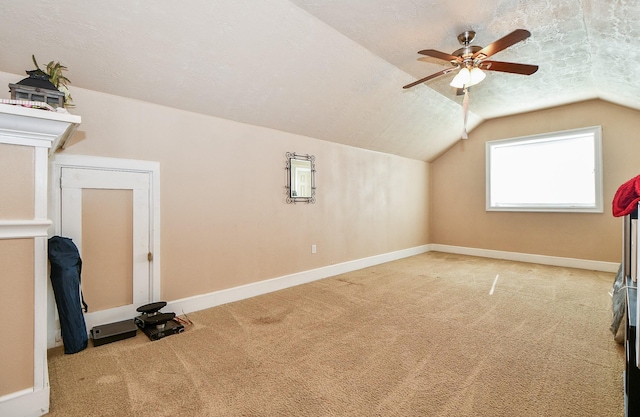 additional living space featuring lofted ceiling, ceiling fan, light colored carpet, and a textured ceiling