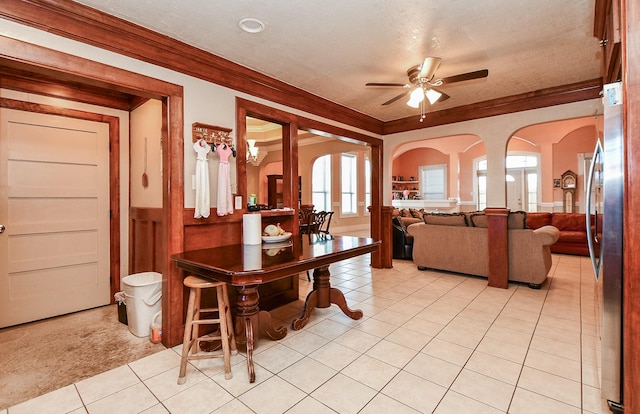 carpeted dining space featuring crown molding, ceiling fan, and a textured ceiling