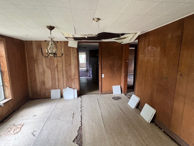 unfurnished dining area with wood walls and an inviting chandelier