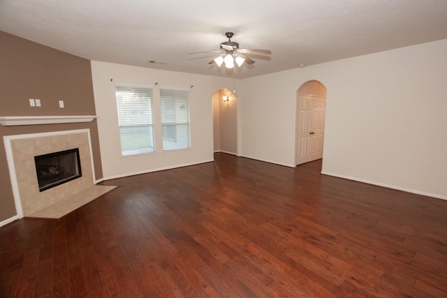 unfurnished living room with a tiled fireplace, ceiling fan, and dark hardwood / wood-style floors