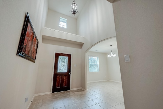 tiled entrance foyer featuring a high ceiling, a healthy amount of sunlight, and a notable chandelier