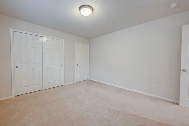 unfurnished bedroom with a closet and light colored carpet