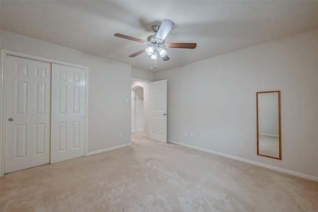 unfurnished bedroom featuring ceiling fan, light colored carpet, and a closet