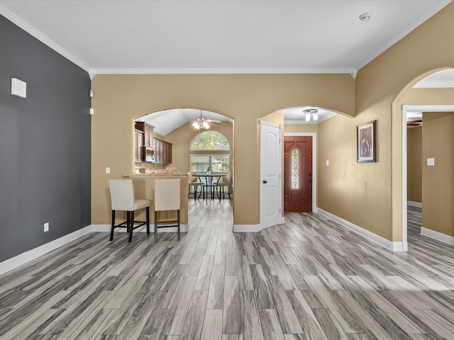 foyer with crown molding, ceiling fan, dark wood-type flooring, and vaulted ceiling