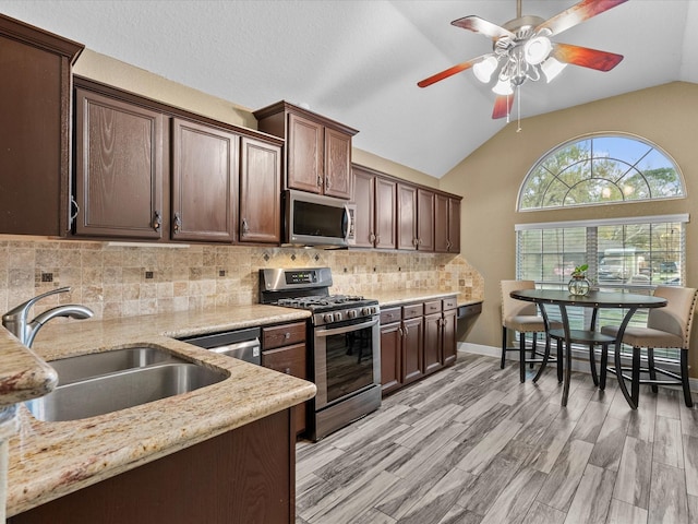 kitchen featuring dark brown cabinetry, stainless steel appliances, lofted ceiling, and sink