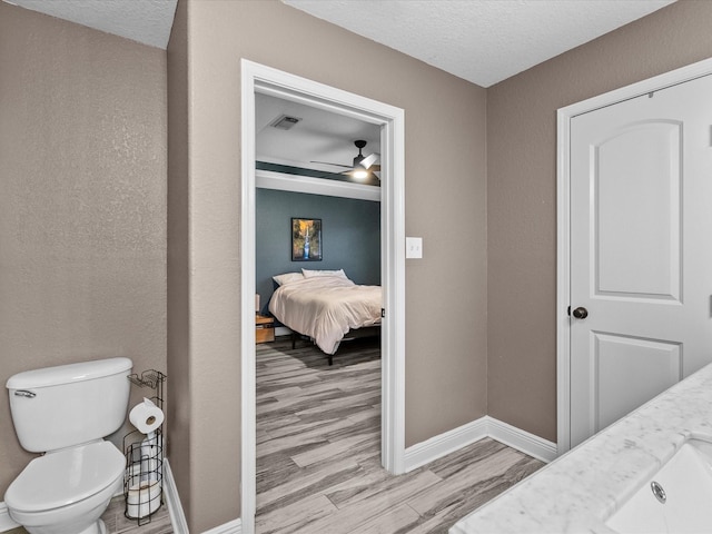 bathroom with vanity, a textured ceiling, ceiling fan, hardwood / wood-style floors, and toilet