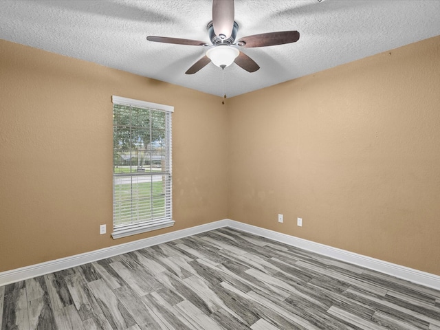 empty room featuring a textured ceiling, hardwood / wood-style flooring, plenty of natural light, and ceiling fan