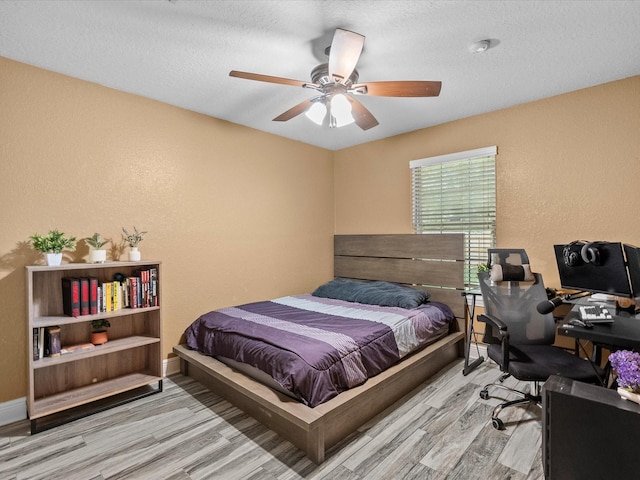 bedroom featuring ceiling fan, light wood-type flooring, and a textured ceiling