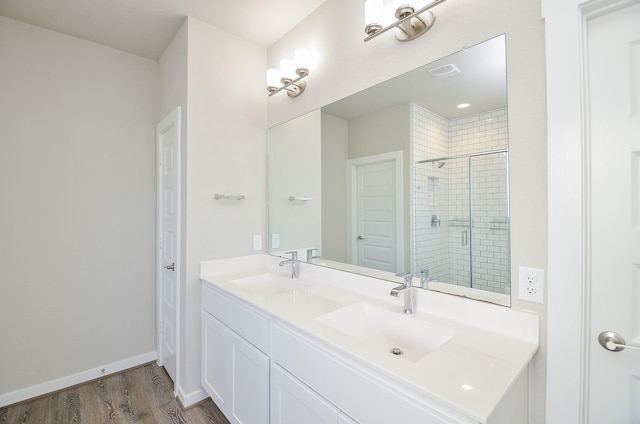 bathroom with hardwood / wood-style floors, vanity, and an enclosed shower