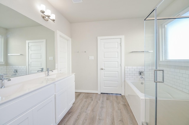 bathroom with hardwood / wood-style flooring, vanity, backsplash, and plus walk in shower