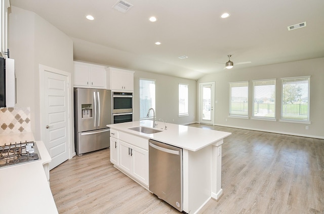 kitchen with light wood-type flooring, stainless steel appliances, sink, a center island with sink, and white cabinets