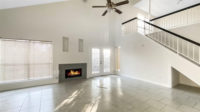 unfurnished living room featuring a high ceiling, light tile patterned floors, french doors, and ceiling fan