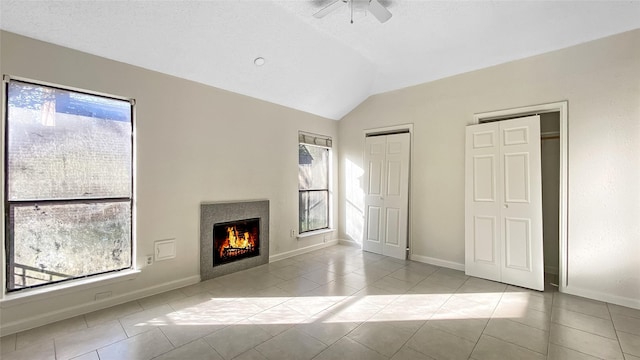 unfurnished living room featuring a wealth of natural light, ceiling fan, lofted ceiling, and light tile patterned floors