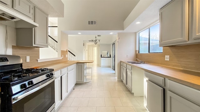 kitchen featuring a chandelier, decorative backsplash, gas stove, and light tile patterned floors