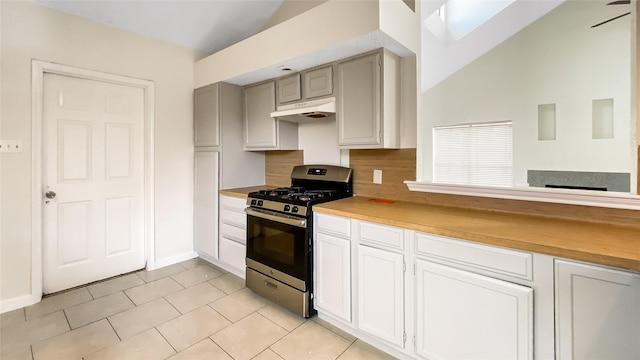 kitchen featuring butcher block countertops, light tile patterned flooring, stainless steel range with gas cooktop, and vaulted ceiling