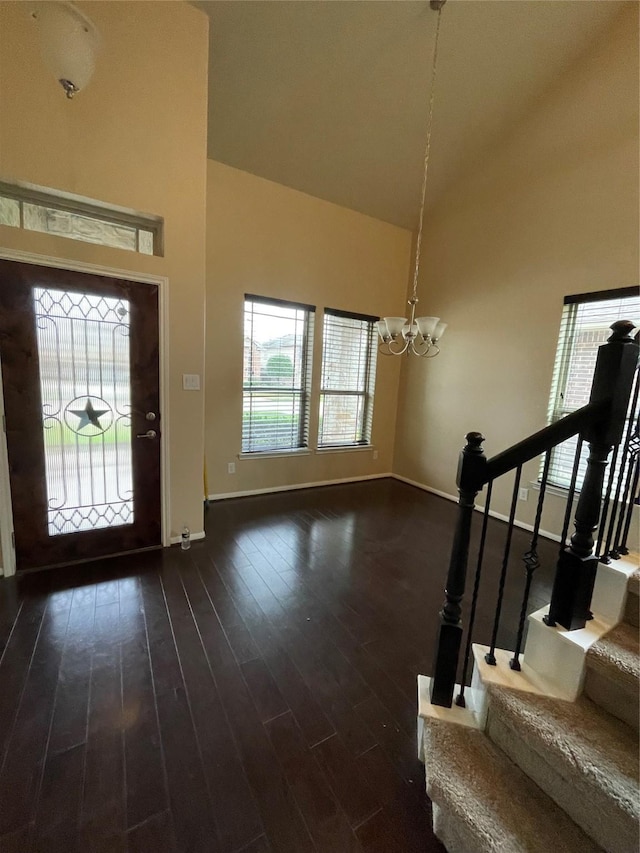 entryway featuring a towering ceiling, dark wood-type flooring, and a notable chandelier