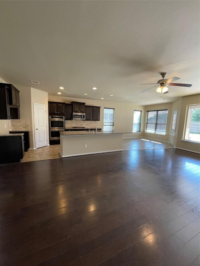 unfurnished living room featuring ceiling fan, light hardwood / wood-style flooring, and a textured ceiling