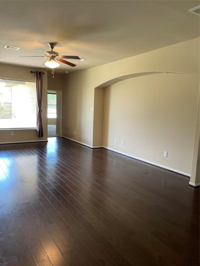 empty room featuring ceiling fan, dark wood-type flooring, and a textured ceiling