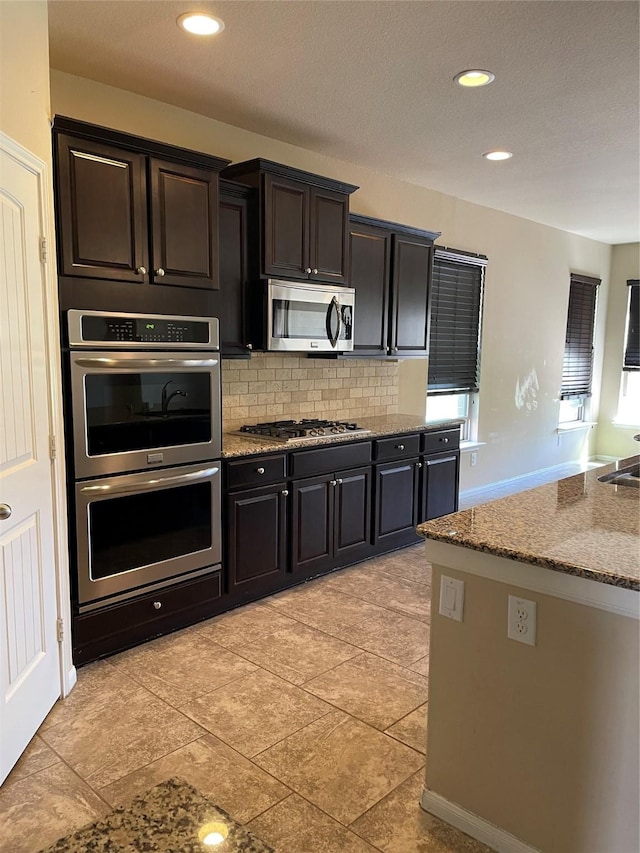 kitchen featuring backsplash, light stone counters, light tile patterned floors, and stainless steel appliances