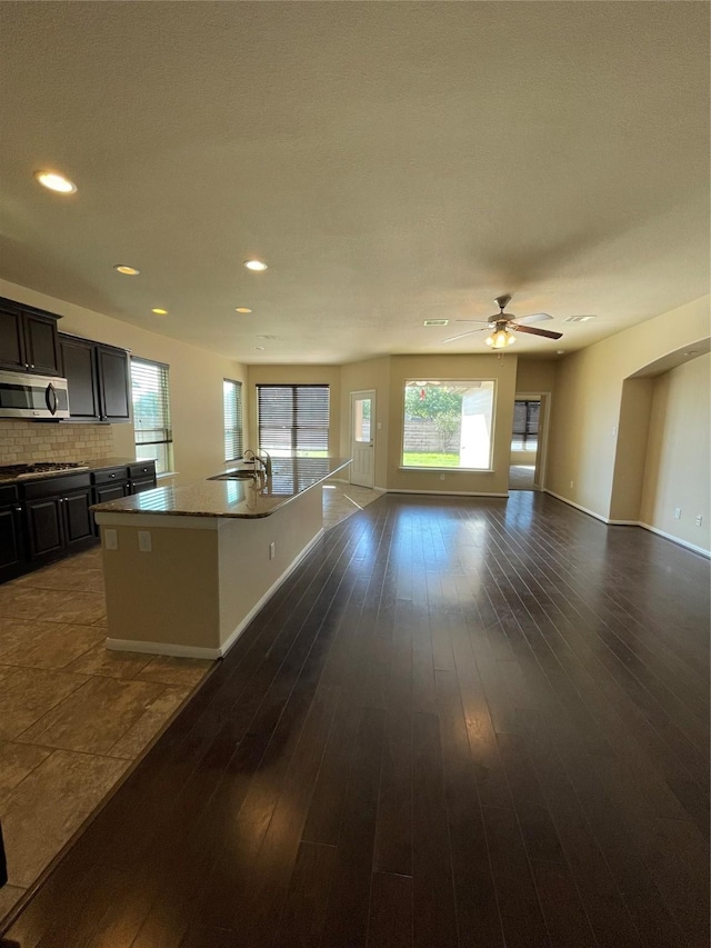 kitchen featuring a kitchen island with sink, sink, appliances with stainless steel finishes, tasteful backsplash, and dark hardwood / wood-style flooring