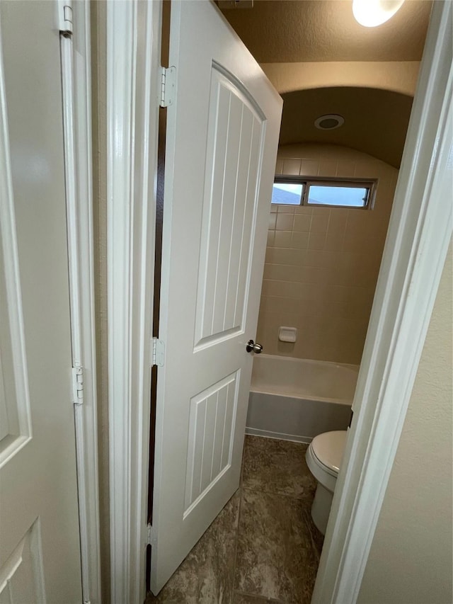 bathroom featuring tile patterned flooring, a bath, and toilet