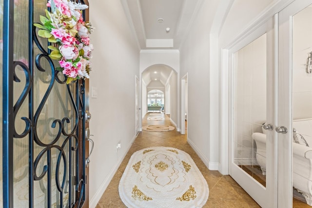 corridor with light tile patterned floors, french doors, and crown molding