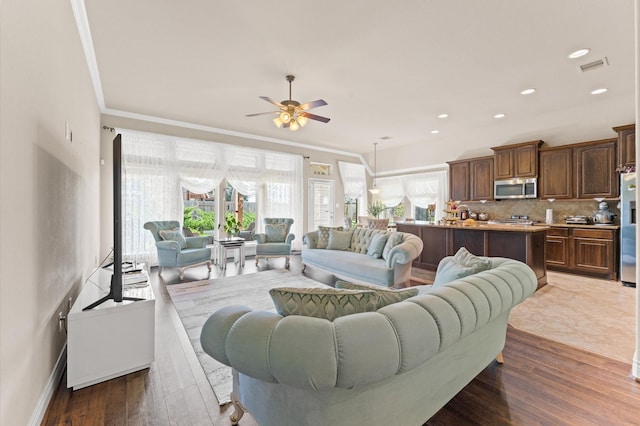 living room featuring hardwood / wood-style flooring, ceiling fan, and crown molding