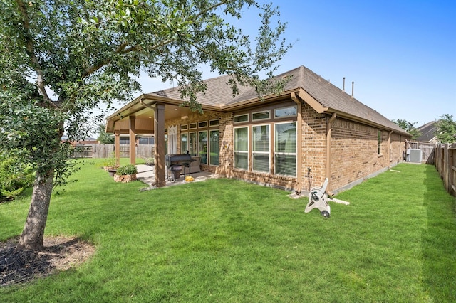 rear view of house featuring a patio, central AC, and a lawn